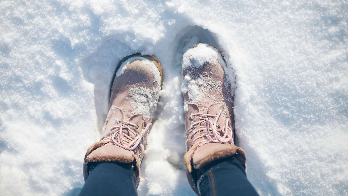 A close-up view of pink winter boots covered in fresh snow, capturing the essence of a chilly, snowy day.