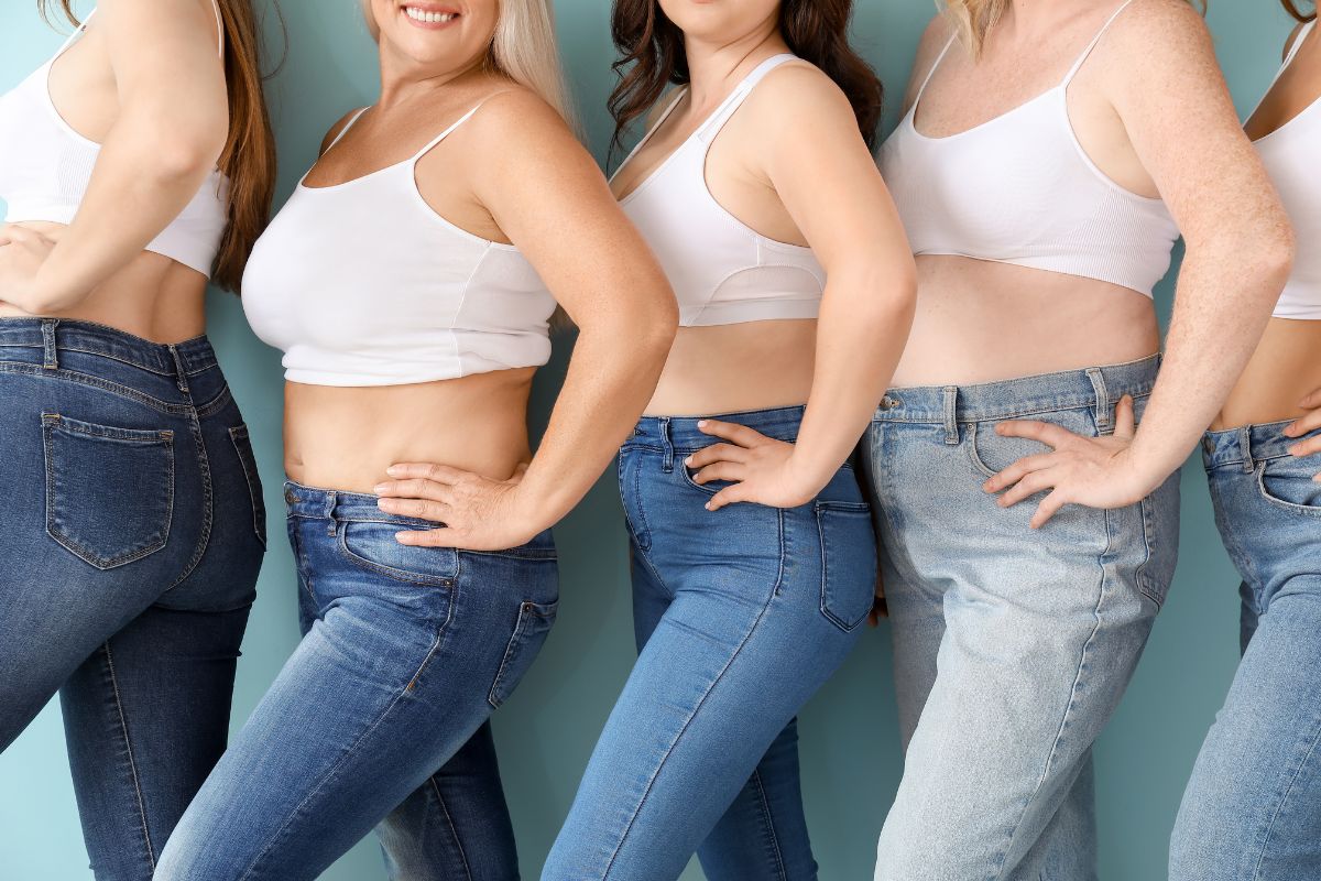 Group of women in different styles of jeans and white tops standing side by side.