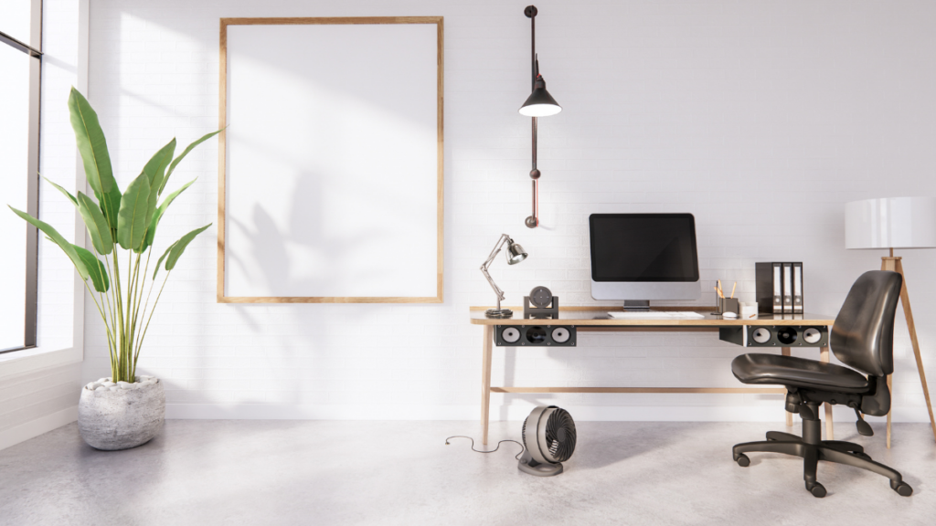 Minimalist office with a desk, monitor, black chair, plant, and blank framed board against a white brick wall.