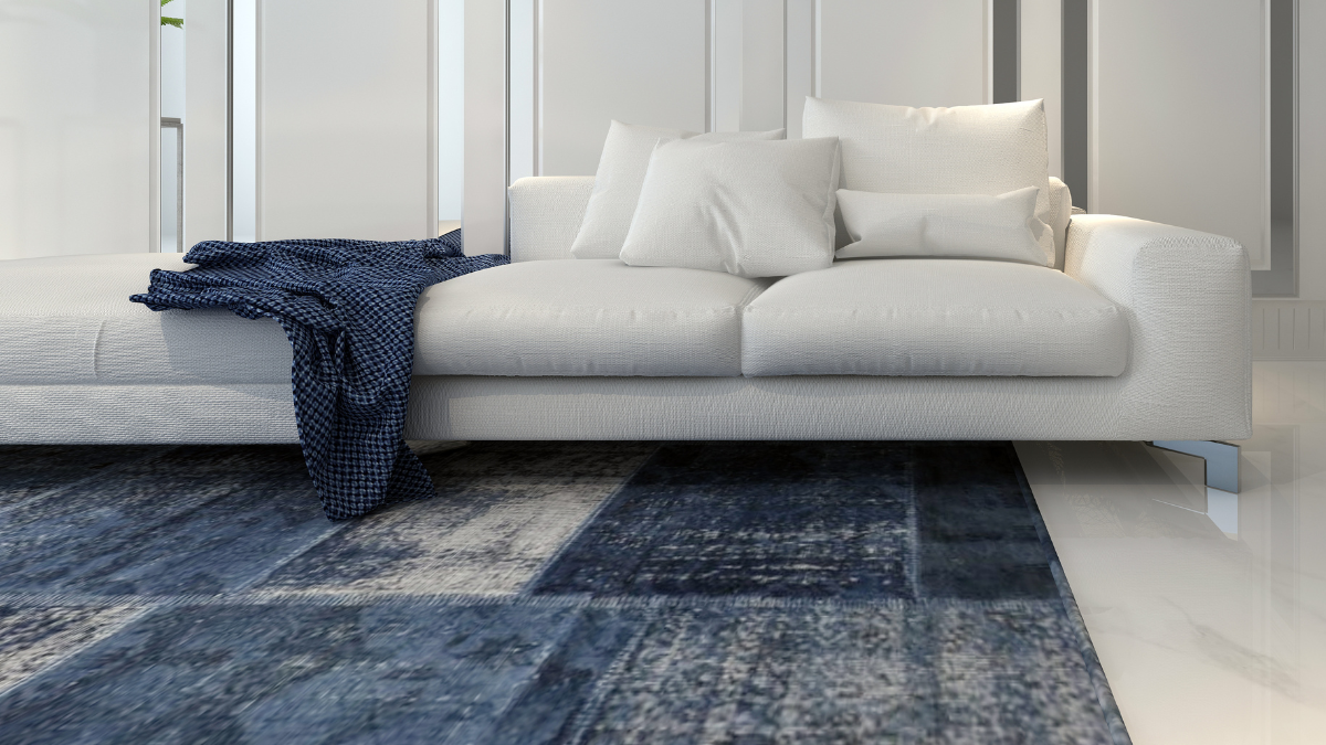 Modern living room with a plush white sofa adorned with cozy pillows, a navy blue throw, and a textured blue area rug, creating a serene and elegant ambiance.