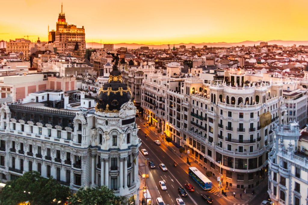Scenic view of Madrid's Gran Vía at sunset, featuring historic buildings and bustling city streets.