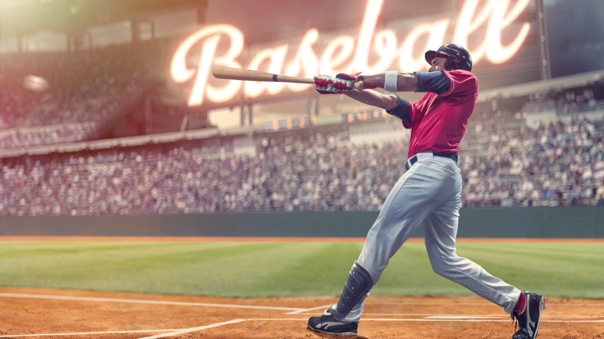 Baseball player in a red jersey swinging a bat during a game, with a packed stadium and 'Baseball' illuminated in the background.