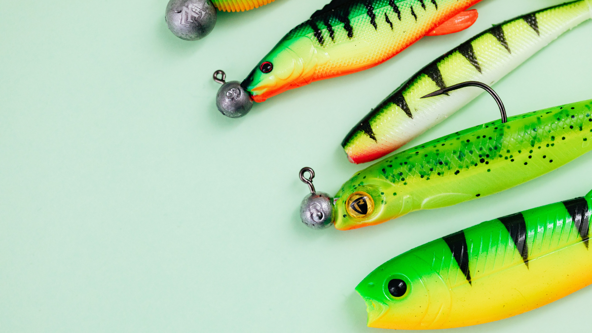 A fishing tackle box filled with lures, hooks, and bait, alongside a spinning reel and fishing rod. Ideal for anglers preparing for a fishing trip.