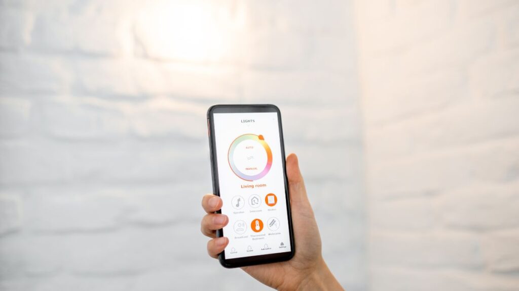 A person holding a smartphone showing a control panel for adjusting the lights.