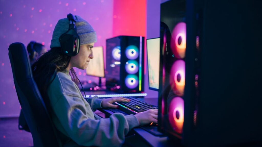 A gamer wearing a headset is focused on playing a PC game in a setup with colorful lights.