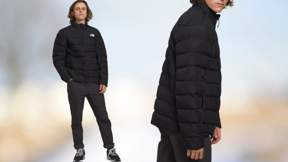 A man wearing a black North Face Aconcagua 3 Jacket, standing casually against a soft, blurred background, showing the jacket’s fit and quilted design.