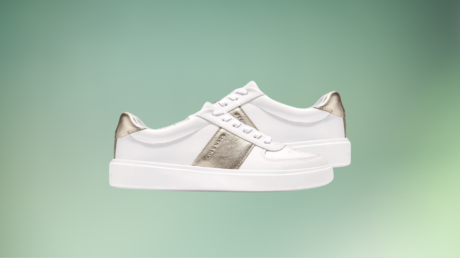 A pair of white sneakers with metallic gold accents displayed against a gradient green background.
