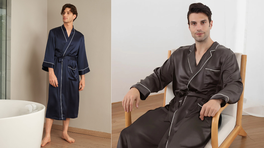 Two men wearing satin robes; one standing in a navy blue robe near a bathtub, the other sitting in a dark brown robe on a wooden chair.