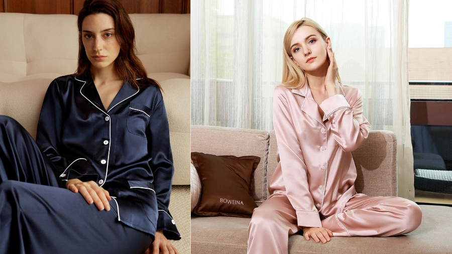 Two women in satin pajama sets; one in navy blue sitting on a bed, the other in blush pink lounging on a sofa near a window.