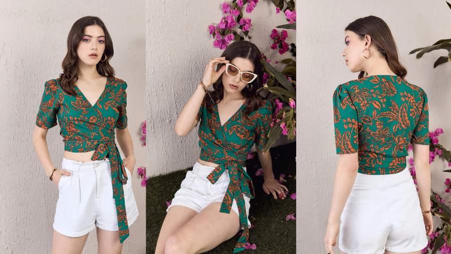 Woman wearing a green wrap top with an orange floral print, paired with high-waisted white shorts, posing in different angles against a floral background.